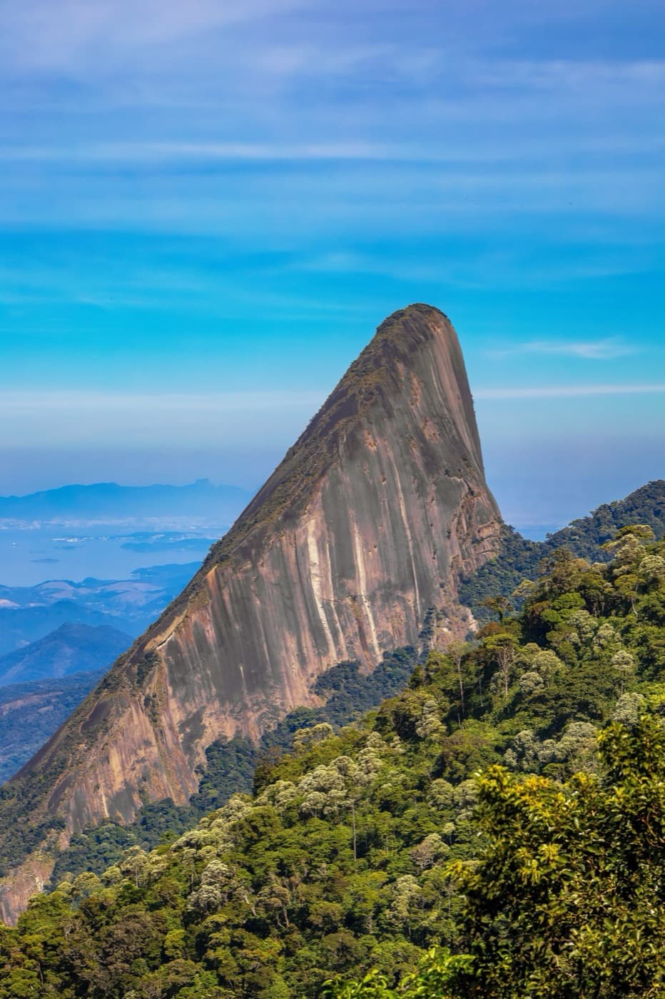 Face rochosa do Escalavrado em formato de proa, com a Baía de Guanabara ao fundo