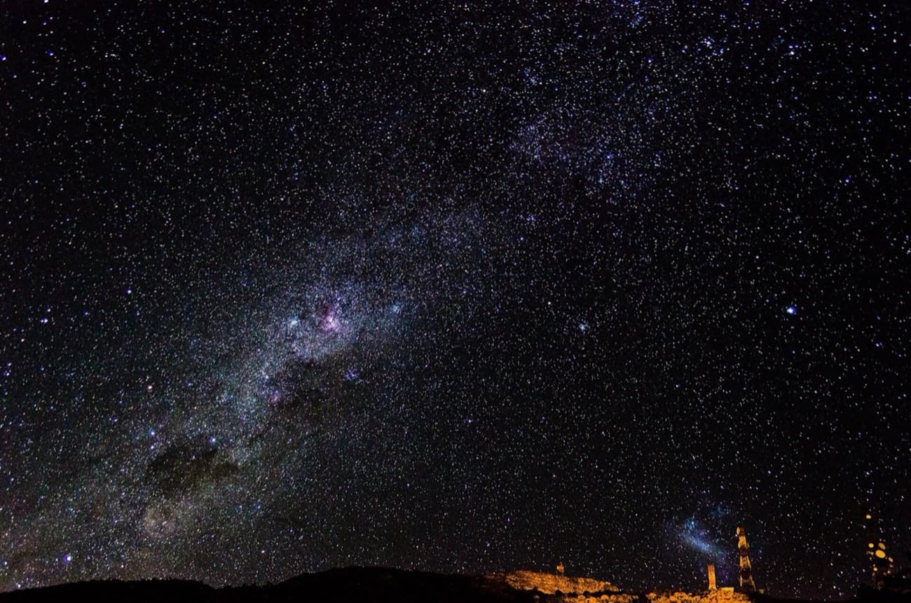 Via Láctea sobre o Pico da Caledônia, com as luzes das torres de transmissão no horizonte