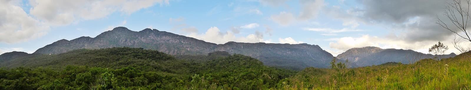 Panorama da Serra do Caraça com o Pico da Carapuça, o Beiço do Diabo e o Pico do Sol acima da mata