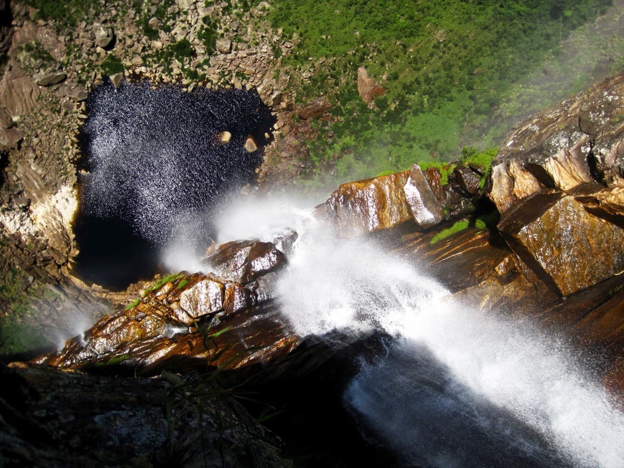 Vista do alto da Cachoeira do Tabuleiro, com a água se desfazendo em spray sobre o abismo