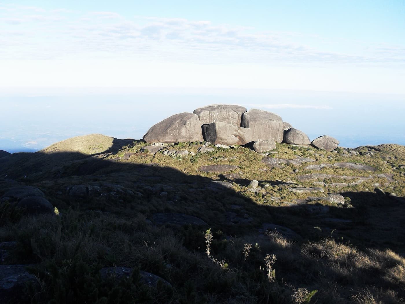 Blocos de granito dos Castelos do Açu sobre o campo de altitude no fim da tarde