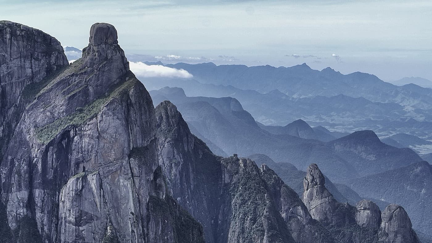 Formações rochosas vistas na travessia, com a torre do Garrafão em destaque e as serras em camadas ao fundo