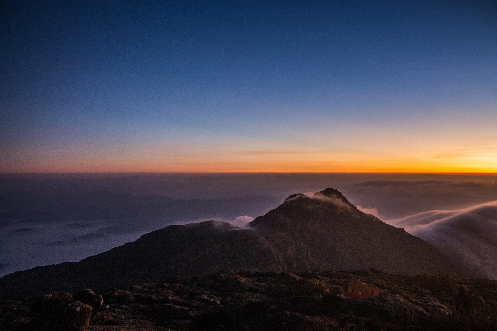 Amanhecer alaranjado sobre um mar de nuvens, em foto feita no cume do Pico dos Marins