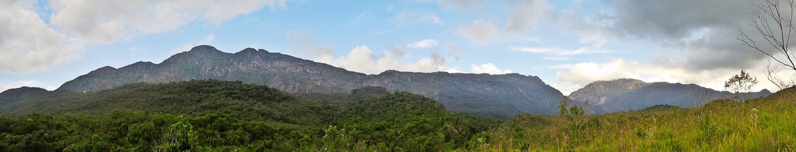 Panorama da Serra do Caraça com o Pico da Carapuça, o Beiço do Diabo e o Pico do Sol acima da mata