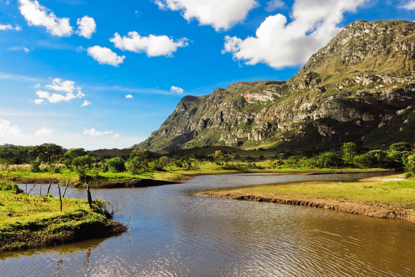 Lagoa da Lapinha da Serra com a serra rochosa iluminada pelo sol ao fundo