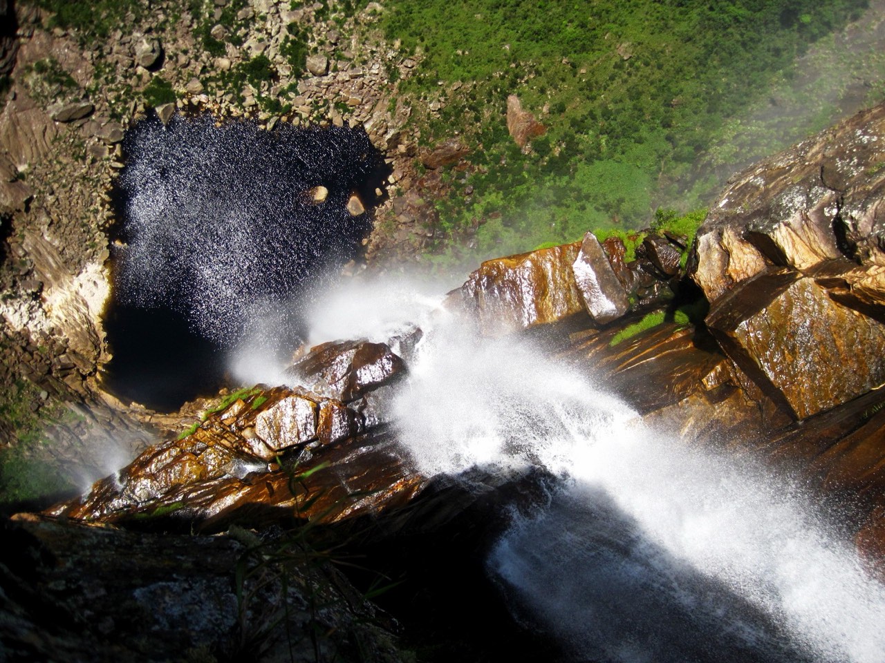 Vista do alto da Cachoeira do Tabuleiro, com a água se desfazendo em spray sobre o abismo